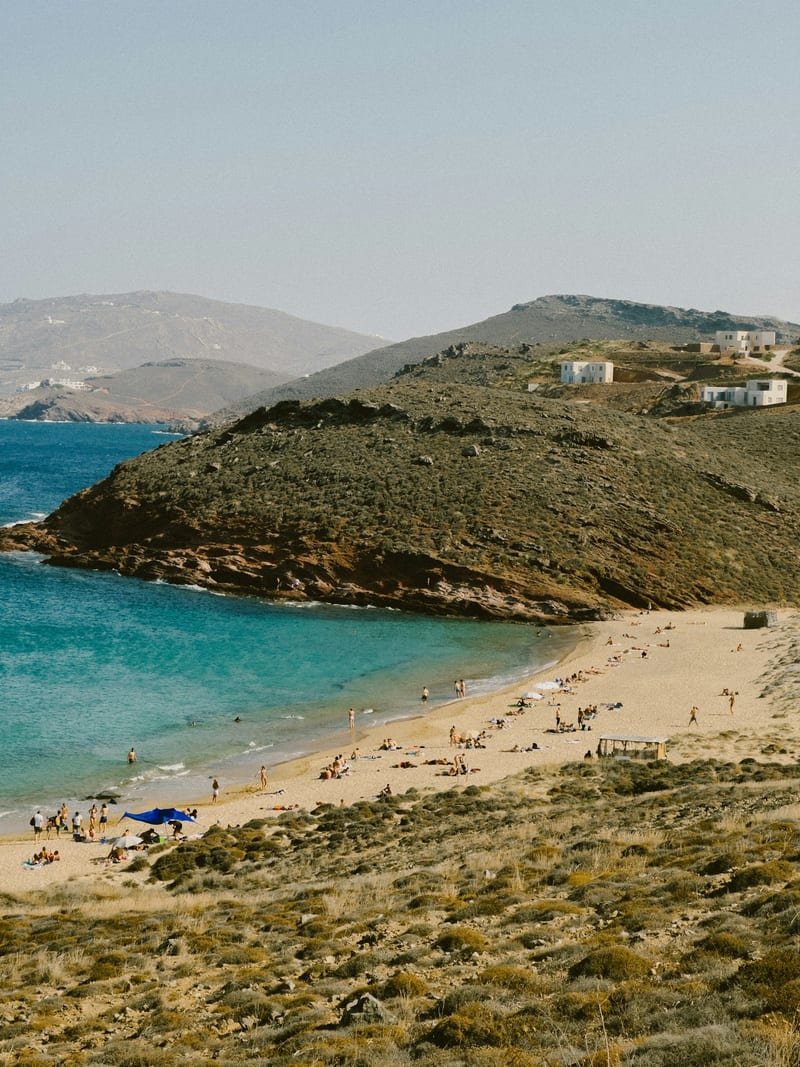 Visitors walking a quiet sandy Mykonos beach